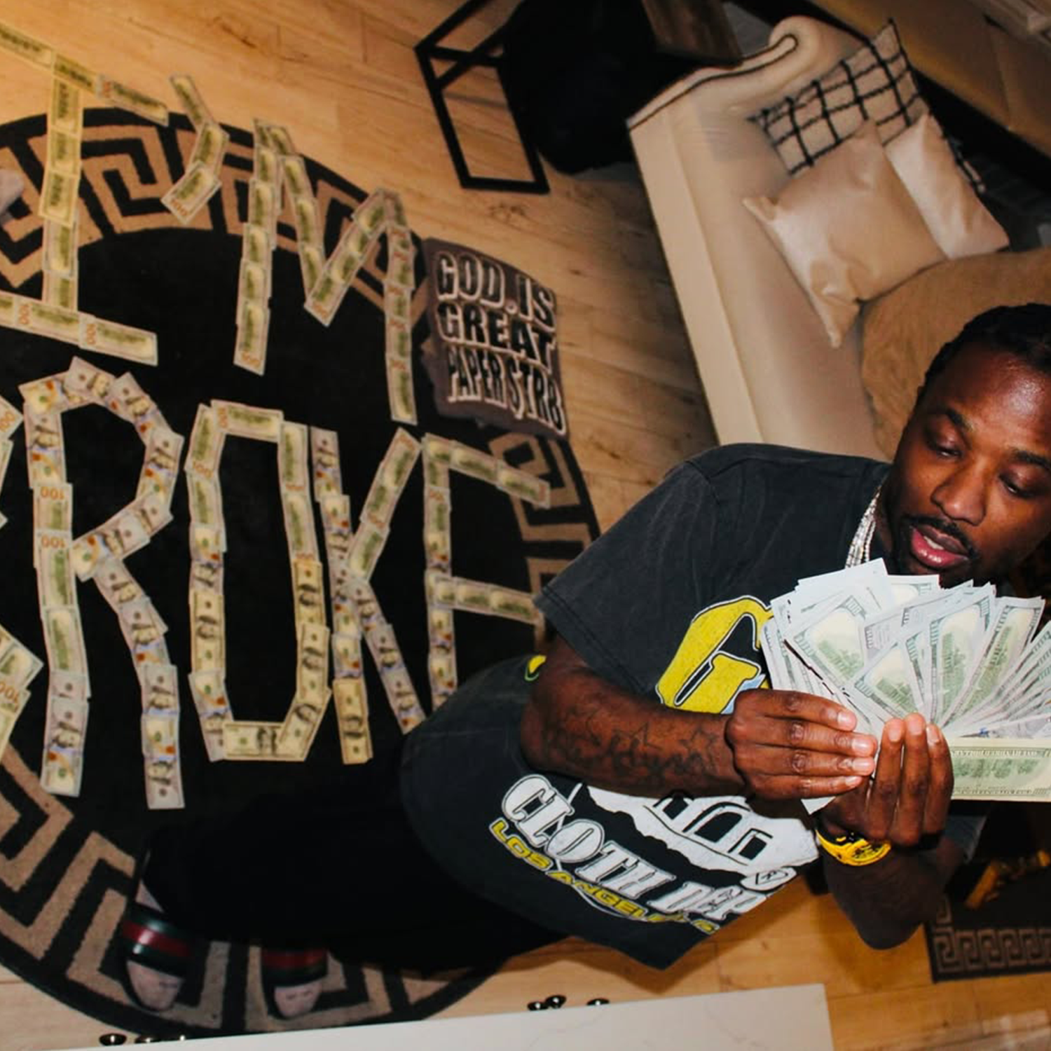 Troy Ave holding money with a GIGPS Clothing Department tee with "I'M broke" spelled in cash.