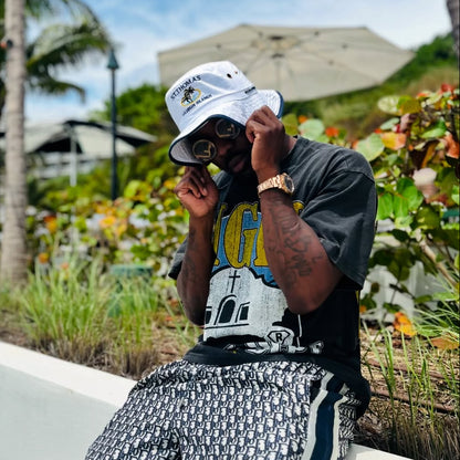 Troy Ave wearing a GIPS Clothing Department Tee in a tropical setting with palm trees.